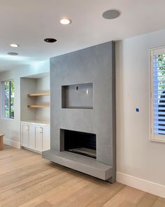 an empty living room with a fireplace and built in shelves on the wall next to it