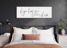 a bedroom with a bed, nightstands and a large framed sign on the wall