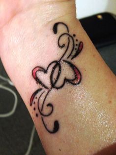 a woman's wrist with a tattoo on it that has hearts and swirls