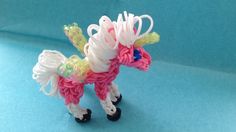 a small toy pony made out of plastic beads on a blue surface with white and pink trimmings