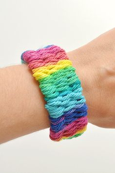 a person's arm with a bracelet made out of multicolored yarn on it