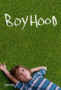 a young boy laying on the grass with his hands up in front of him that says boyhood