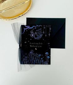 a black and white card with an image of a dragon on it next to a gold plate