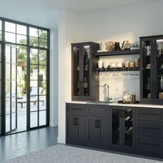 a kitchen with black cabinets and white counter tops next to a glass doored window