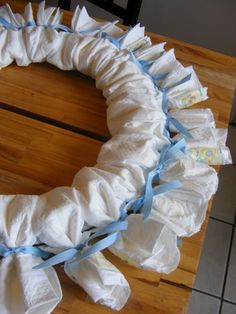 a wreath made out of toilet paper sitting on top of a wooden table with blue ribbon around it