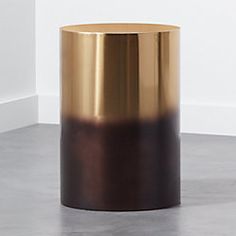 a gold and black round table sitting on top of a cement floor next to a white wall