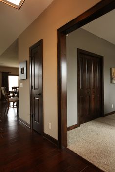 an empty living room with hardwood floors and two doors leading to the dining room area