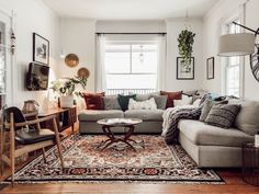 a living room filled with lots of furniture next to a tall clock mounted on the wall