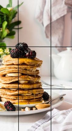 a stack of pancakes topped with berries and syrup on top of a white plate next to flowers