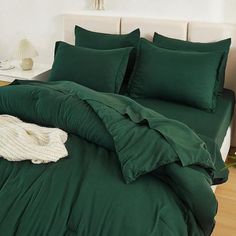 a bed with green sheets and pillows on it