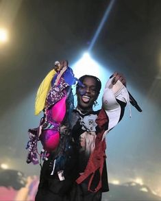 a man standing in front of a stage with clothes on his shoulders and hands up