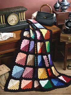 a crocheted blanket sitting on top of a wooden floor next to a table