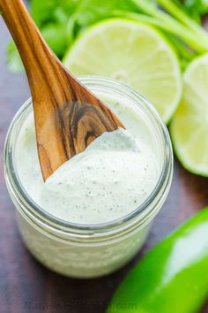 a wooden spoon sitting in a jar filled with white sauce and garnished with cilantro