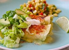 a blue plate topped with food next to a pile of corn and lettuce