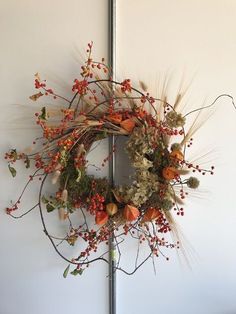 a wreath is hanging on the wall with red berries and other foliages around it