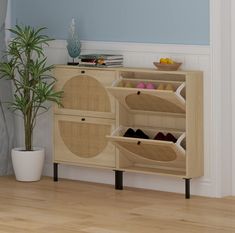 a wooden cabinet with baskets and shoes on it next to a potted plant in a room