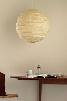 a table with a book, coffee cup and paper lantern hanging from it's ceiling