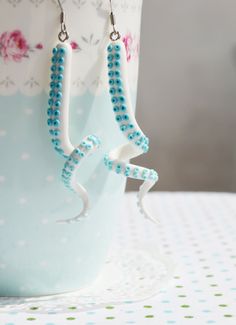 a pair of white and blue beaded earrings sitting on top of a cup