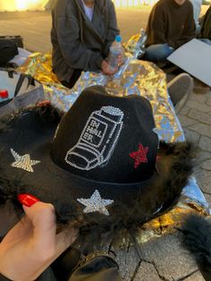 a person wearing a black hat with silver writing on it and stars around the brim