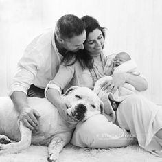 a man, woman and baby are cuddling with a dog