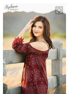 a beautiful young woman leaning on a fence