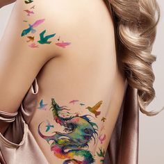 the back of a woman's body with colorful tattoos on her left shoulder and chest