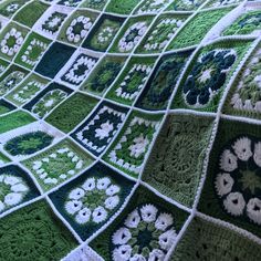 a green and white crocheted blanket on top of a bed covered in flowers