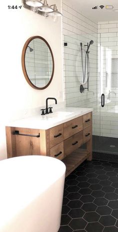 a bathroom with two sinks and a bathtub in the corner, along with a large mirror on the wall