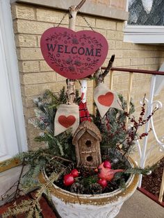 a welcome sign hanging from the side of a building next to a potted plant