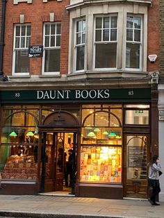 a store front with many books on display in the windows and people walking past it