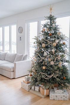 a living room with a christmas tree in the corner and presents on the floor next to it