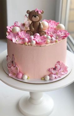 a pink cake decorated with flowers and a teddy bear