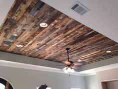 a ceiling made out of wood planks in a living room with fan and light