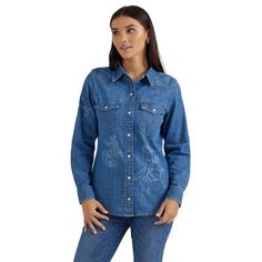 Down to the smallest detail, our Women's Wrangler Retro Denim Slim Cowboy Snap Shirt is a true classic. It's cut from lightweight denim made of 100% cotton for lasting comfort and quality. Vintage-inspired with a slimmer cut than our most popular denim shirt, its one-point yokes, chest pockets with flaps, "W" pocket stitching, and pearl snaps will deliver the Western authenticity every outfit needs. Worn alone or layered, it'll always be a favorite. Slim FIt Western Front & Back Yokes Snap Buttons Long Sleeve Classic "W" Stitching 100% Cotton Dark Wash Cotton Tops For Rodeo, Western Style Relaxed Fit Medium Wash Tops, Spring Denim Shirt For Rodeo, Casual Denim Top For Rodeo, Relaxed Fit Medium Wash Shirt For Rodeo, Relaxed Fit Denim Tops For Rodeo, Dark Wash Relaxed Fit Top For Rodeo, Western Style Dark Wash Relaxed Fit Tops, Western Style Denim Blue Cotton Tops