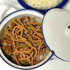 two bowls filled with food and rice on top of a white tablecloth next to each other