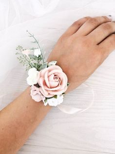 a person's hand with a flower on it and a white ribbon around the wrist