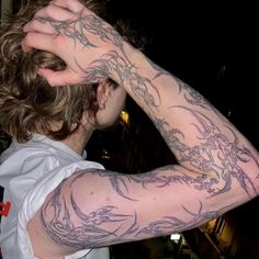 a man with tattoos on his arm covering his eyes