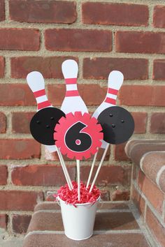 a cup filled with cake pops covered in pink and black frosting next to a brick wall