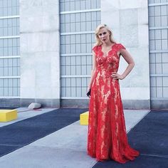 a woman in a red dress is posing for a photo outside the building with her hands on her hips