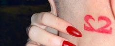 a close up of a person's face with red nail polish on her nails