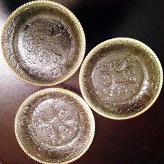 three glass bowls sitting on top of a wooden table next to each other with designs