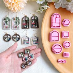 a hand is shown next to some miniature magnets on a wooden tray with flowers