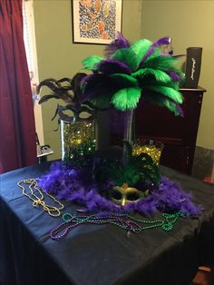 a table topped with purple, green and gold mardi gras decorations