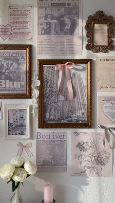 a wall covered in pictures and photos next to a vase with flowers