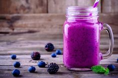 a purple smoothie in a mason jar surrounded by berries