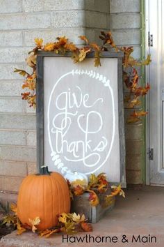 a sign that says give thanks on it next to some pumpkins and autumn leaves