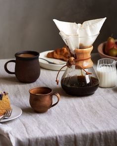 a table topped with cakes and coffee cups