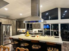 a large kitchen with an island, stove and refrigerator freezer in the center is lit by recessed lights