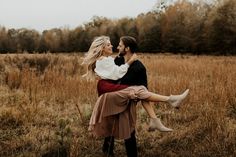 a man carrying a woman on his back in the middle of a field with tall grass