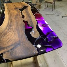 a table that is made out of wood and glass with purple lights on it, sitting in a room